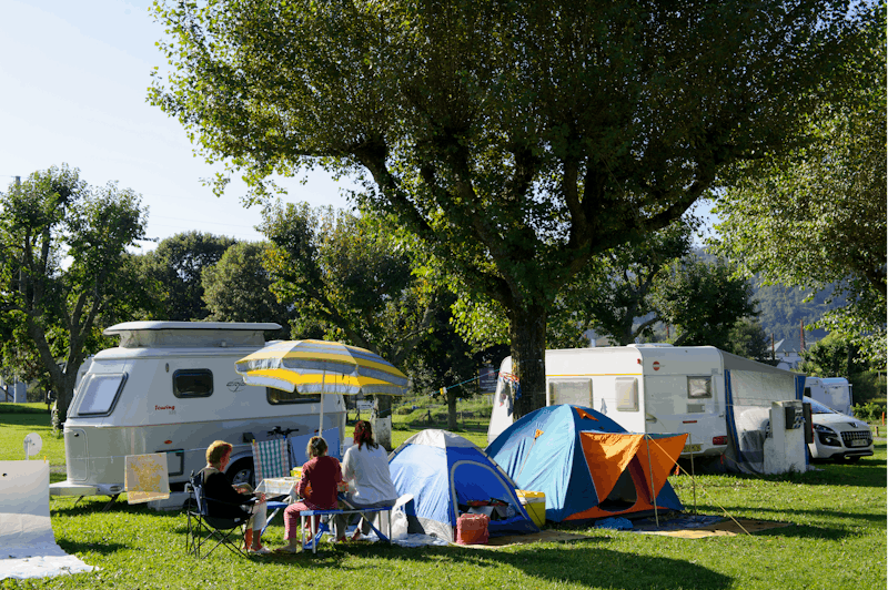 Camping Le Vieux Berger - Sitzende Gäste vor dem Zelt auf der Wiese der Campingplatzanlage