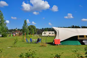 Camping Leiputrija - Wohnwagen auf einem Stellplatz mit Sitzgelegenheiten davor