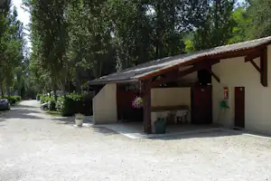 Überdachter Grillplatz am Campingplatz mit Holzdach, Spüle, Feuerlöscher und Sitzbank vor der Hütte.