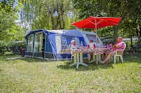 Camping Les 2 Vallées - Camper sitzen unter einem Sonnenschirm vor einem Wohnwagen