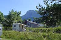 Camping Les 4 Saisons - Wohnmobil auf einem Stellplatz mit Bungalows im Hintergrund