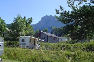 Camping Les 4 Saisons - Wohnmobil auf einem Stellplatz mit Bungalows im Hintergrund