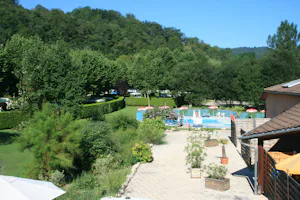 Camping Les 4 Saisons - Blick auf den Swimmingpool und Stellplätze unter Bäumen umringt von Hecken im Hintergrund