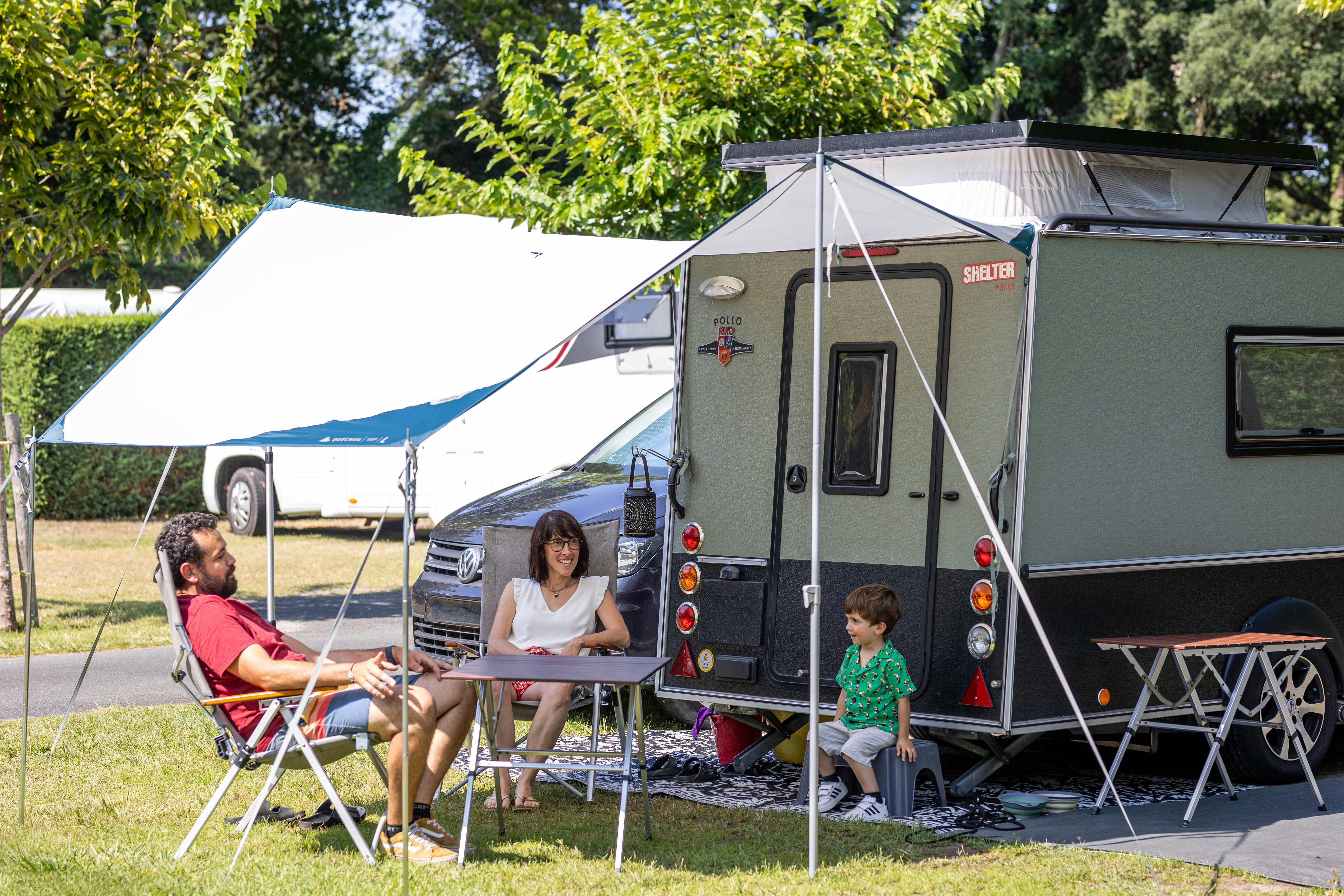 Camping Les Acacias - Familie sitzt auf ihrem Wohnwagenstandplatz