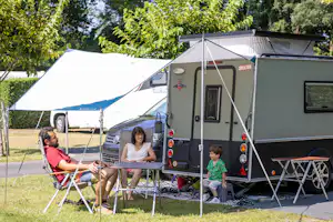 Camping Les Acacias - Familie sitzt auf ihrem Wohnwagenstandplatz