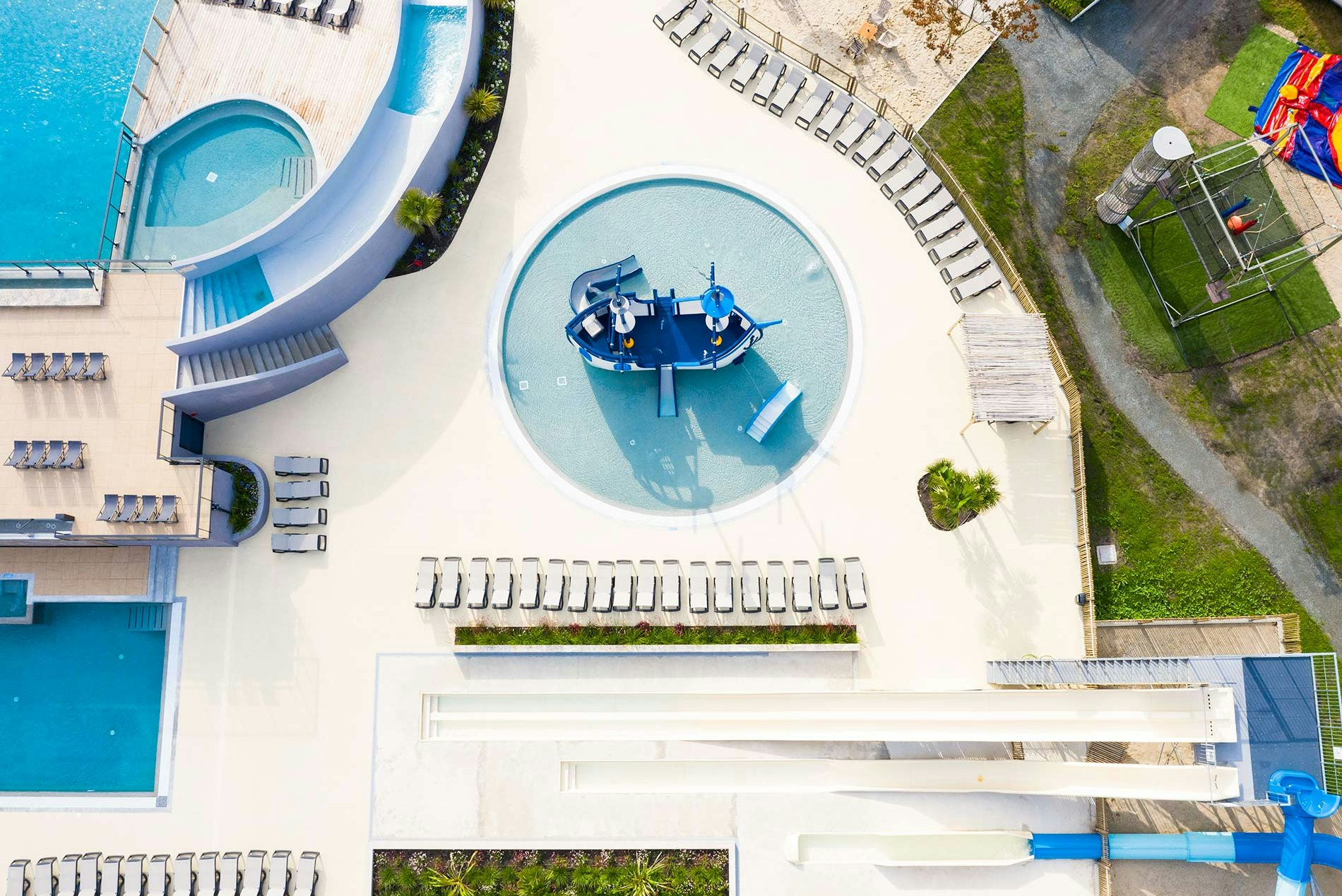 Luftaufnahme von zwei Pools mit Liegen, einem Whirlpool und einem Steg am Campingbereich.