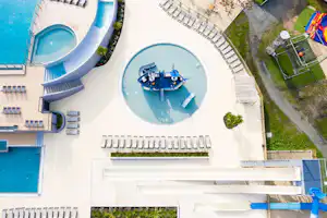 Luftaufnahme von zwei Pools mit Liegen, einem Whirlpool und einem Steg am Campingbereich.