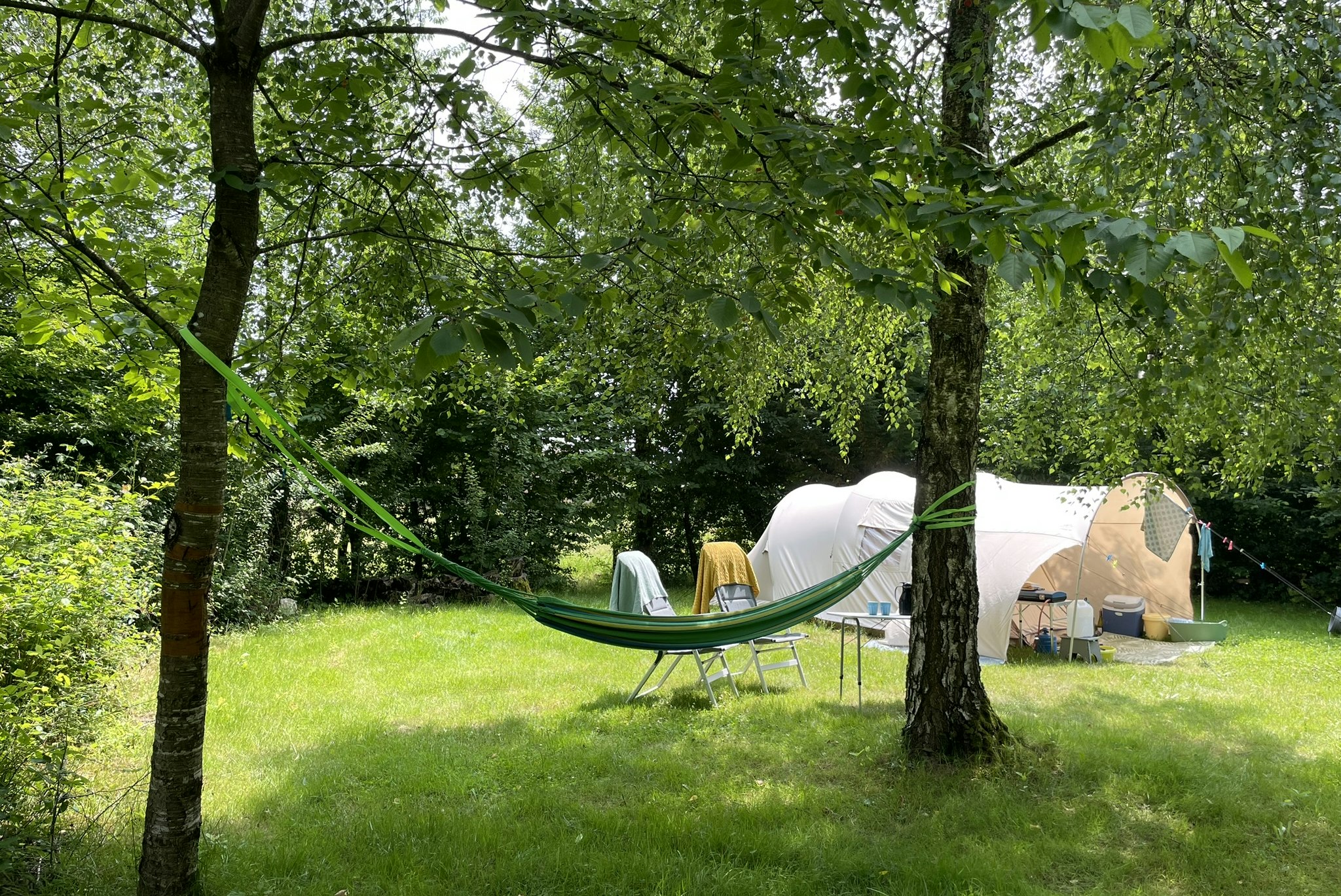 Camping Les Arbois - Blick auf einen Standplatz im Grünen mit Hängematte