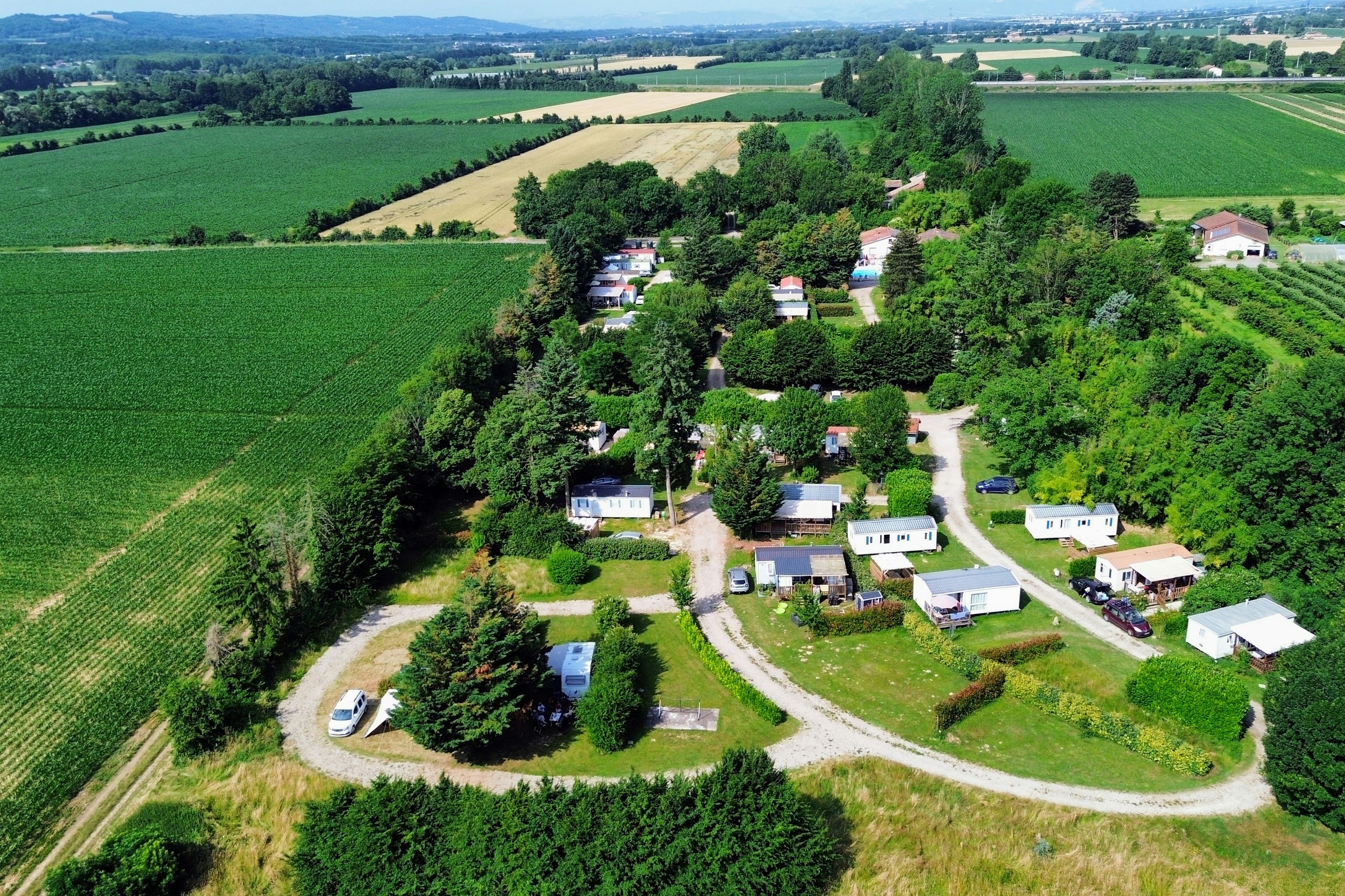 Luftaufnahme eines Campingplatzes im Grünen Tal mit Stellplätzen, Wegen und kleinen Gebäuden zwischen Feldern und Wäldern.