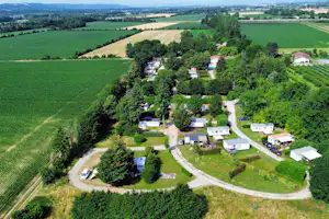 Luftaufnahme eines Campingplatzes im Grünen Tal mit Stellplätzen, Wegen und kleinen Gebäuden zwischen Feldern und Wäldern.