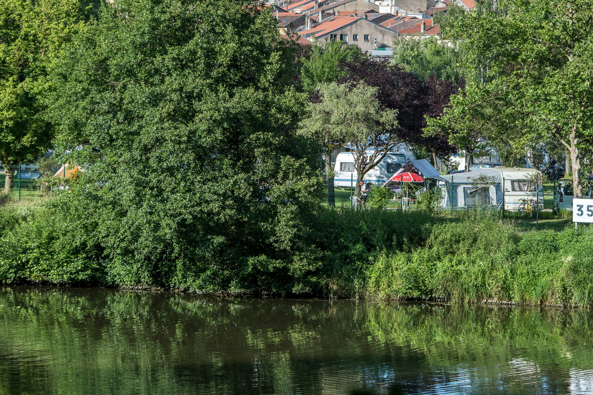 Camping de La Moselle  Camping Les Boucles de La Moselle - Standplätze in Flussnähe umgeben von Bäumen 