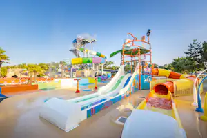 Wasserrutschen und Planschbecken auf einem Campingplatz, mit bunten Rutschen, Geländern und Wasser im Becken.