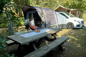 Camping Les Cent Chênes - Camperin entspannt auf einem Standplatz bei einer Picknickbank