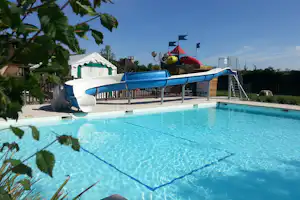 Blauer Wasserrutschbahn-Bereich am Campingpool mit weißem Zelt, Spielgerüst und Bäumen im Hintergrund.