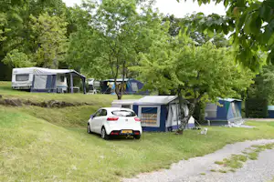 Camping Les Charmilles - Wohnwagen- und Zeltstellplatz zwischen Bäumen auf dem Campingplatz