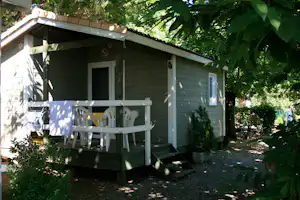 Camping Les Châtaigniers - Holzhütte mit überdachter Veranda auf dem Campingplatz
