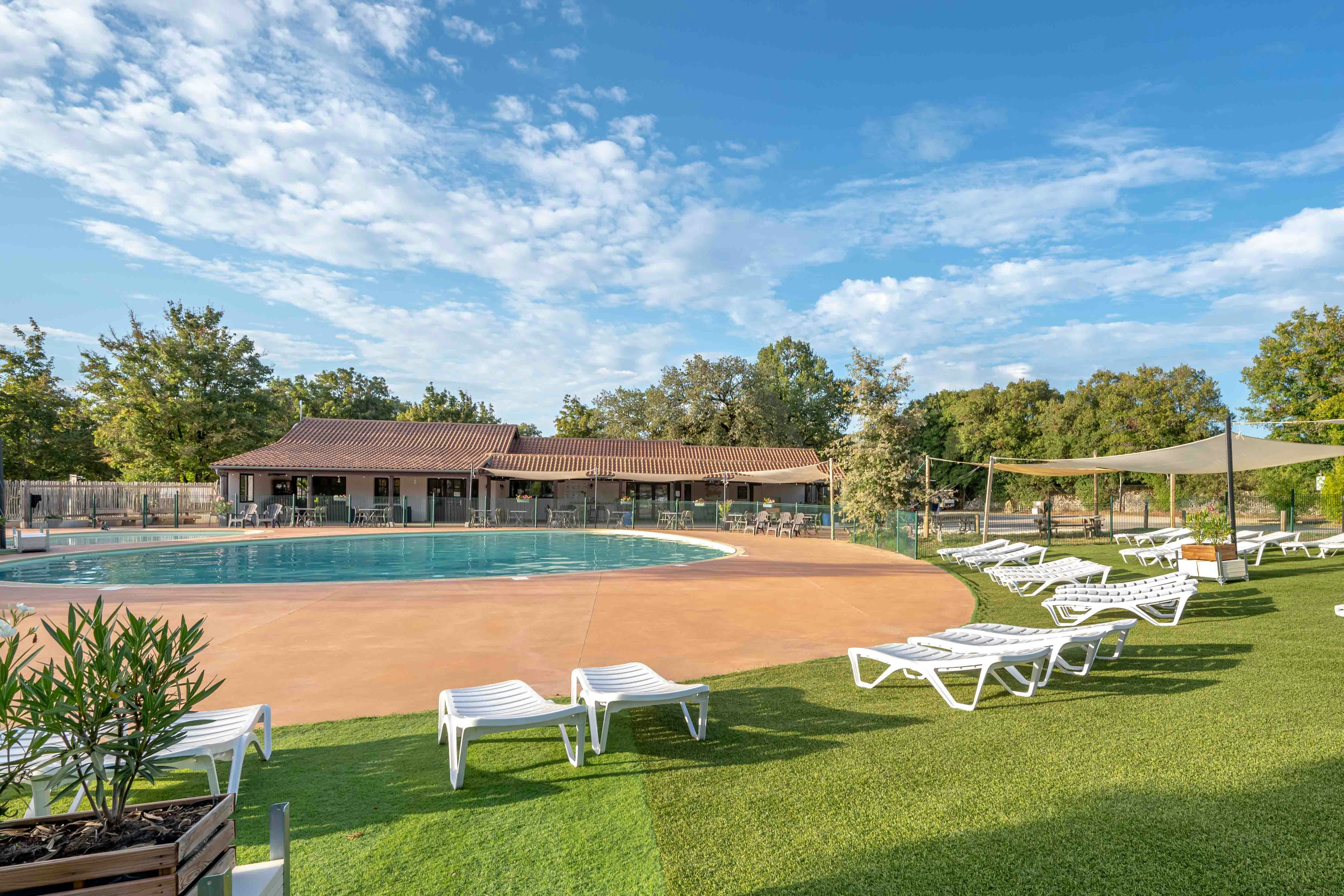 Camping Koawa Les Cigales  Camping Les Cigales - Ciela Village - Liegestühle am Pool des Campingplatzes