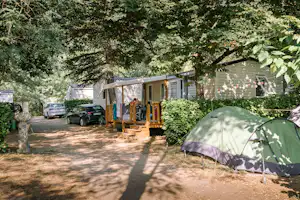 Camping Les Drouilhèdes - Mobilheim mit Terrasse im Schatten der Bäume auf dem Campingplatz