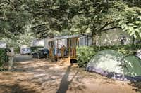 Camping Les Drouilhèdes - Mobilheim mit Terrasse im Schatten der Bäume auf dem Campingplatz