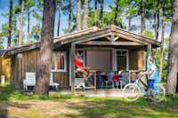 Camping Les Embruns - Mobilheim mit überdachter Veranda zwischen Bäumen