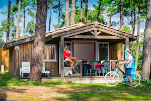 Camping Les Embruns - Mobilheim mit überdachter Veranda zwischen Bäumen