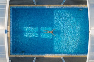 Camping Les Genêts - Person schwimmt im Pool des Campingplatzes