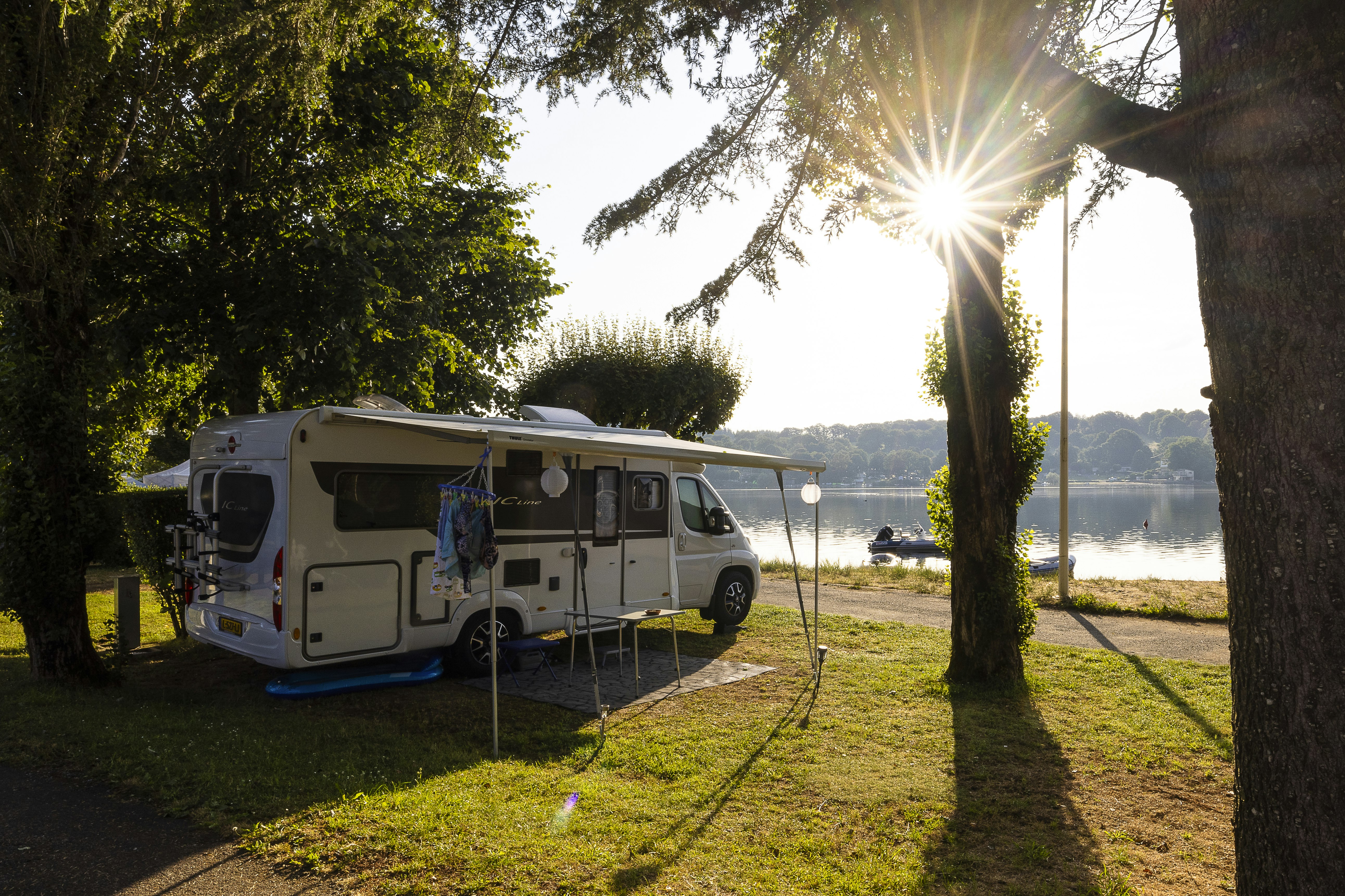 Camping Les Genêts - Standplatz zwischen Bäumen am Wasser