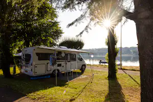 Camping Les Genêts - Standplatz zwischen Bäumen am Wasser