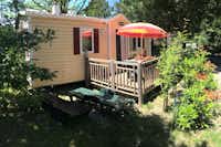 Camping Les Grillons - Mobilheim mit Veranda auf der ein Sonnenschirm steht und Sonnenliegen davor