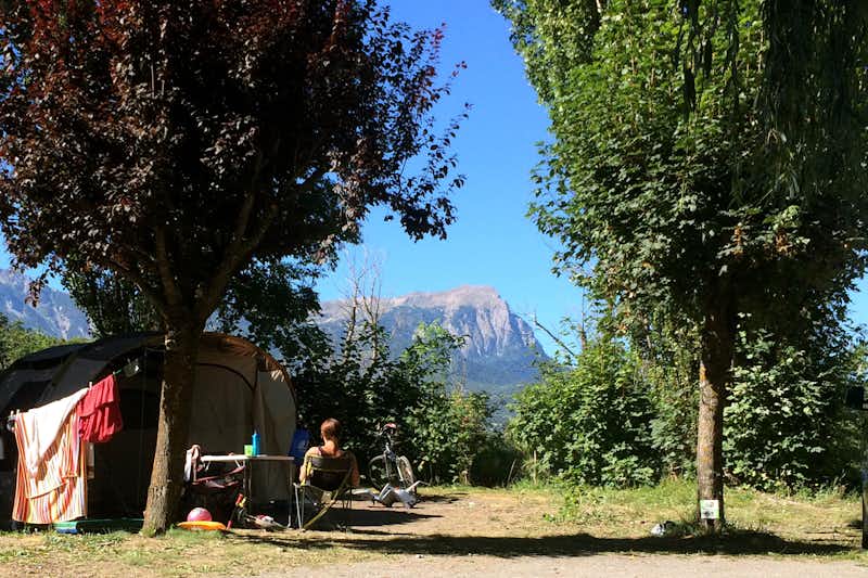 Camping Les Grillons - Zelt auf Stellplatz zwischen Bäumen mit einem Berg der Alpen im Hintergrund