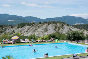Camping Les Hauts de Rosans - Gäste liegen am Pool in der Sonne mit Blick auf die berg im Naturpark des Baronnies Provençales