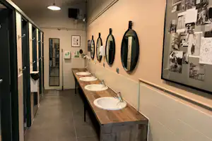 Camping Les Hirondelles - Sanitärbereich vom Campingplatz mit Waschbecken, Spiegeln und Toiletten
