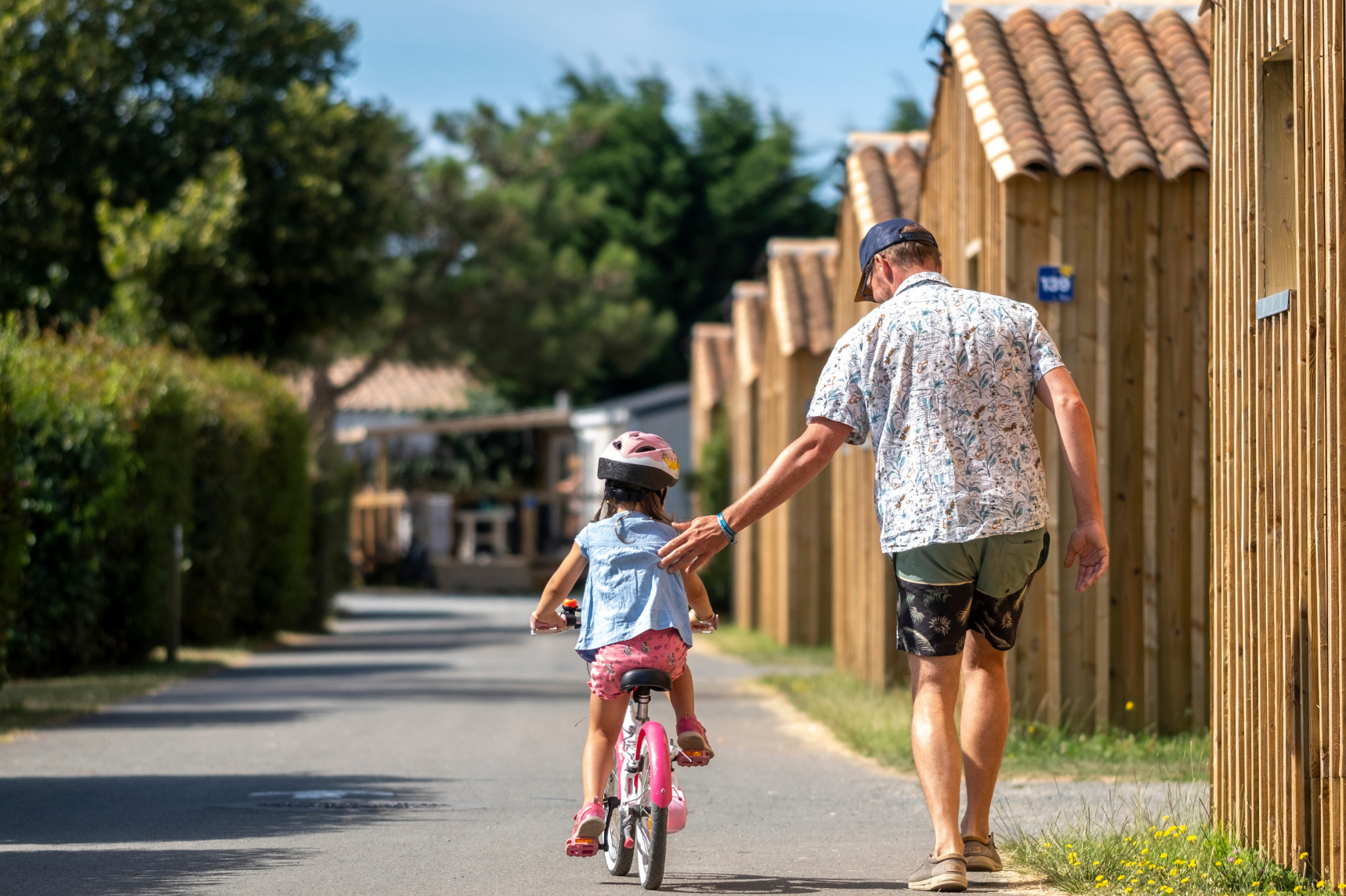 Flower Camping Les Ilates - Vater mit Kind auf einem Fahrrad auf dem Campingplatz