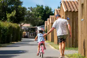 Flower Camping Les Ilates - Vater mit Kind auf einem Fahrrad auf dem Campingplatz