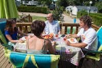 Camping Les Ilots de St. Val - Familie frühstückt auf der Terrasse des Mobilheims im Grünen