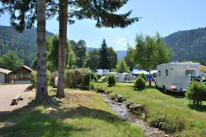 Camping Les Jonquilles - Wohnwagen- und Zeltstellplatz zwischen Bäumen auf dem Campingplatz