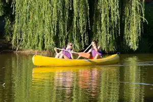 Zwei Personen im gelben Kajak auf dem See, umgeben von Weiden am Ufer.