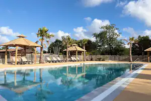 Camping Les Ourmes - Pool im Freien mit Liegestühlen und Sonnenschirmen