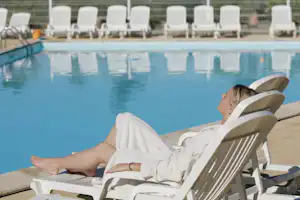 Camping Les Pins du Soleil - Der Gast liegt am Pool in der Sonne