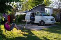 Camping Les Pommiers - Campingvan auf Zeltplatz mit davor sitzender Camperin