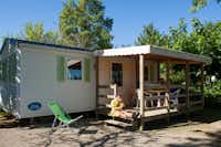 Camping Les Pommiers - Mobilheim mit überdachter Veranda auf der Camper sitzen