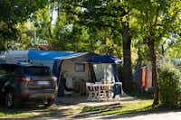 Camping Les Pommiers - Wohnwagen mit Vorzelt  zwischen Bäumen