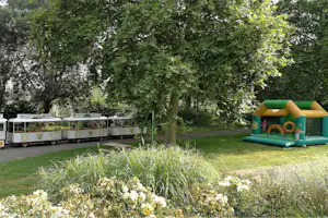 Kinder-Hüpfburg neben Rasenfläche im Campingbereich, im Hintergrund Wohnwagen mit Markisen und Bäume.