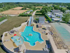 Großes Schwimmbecken mit Sonnenliegen und Sonnenschirmen auf der Terrasse, daneben ein weiteres Becken und gepflegte Wege.