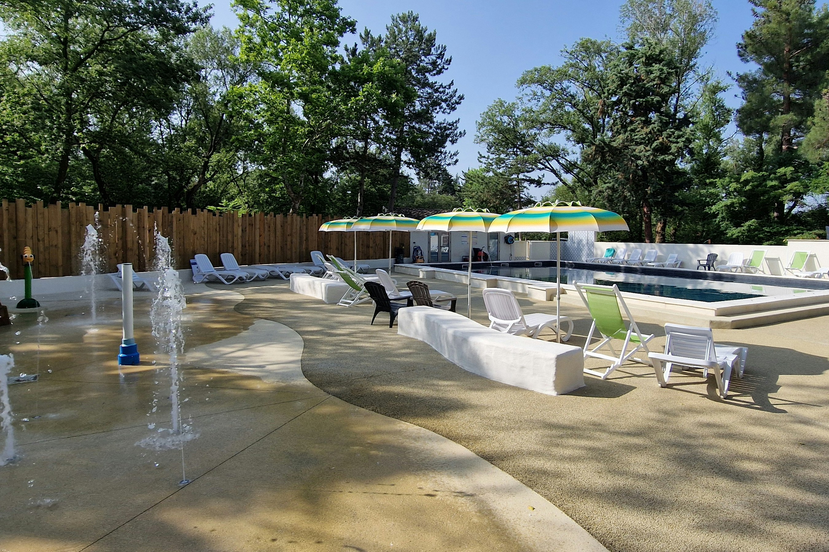 Beheiztes Poolbecken mit mehreren Liegen auf der Terrasse, daneben Springbrunnen und Wege zwischen den Bereichen.