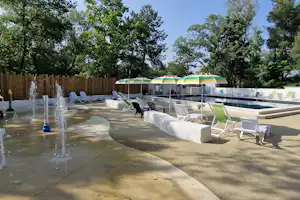 Beheiztes Poolbecken mit mehreren Liegen auf der Terrasse, daneben Springbrunnen und Wege zwischen den Bereichen.