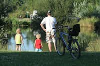Camping Les Saules - Familie mit Fahrrad am See 