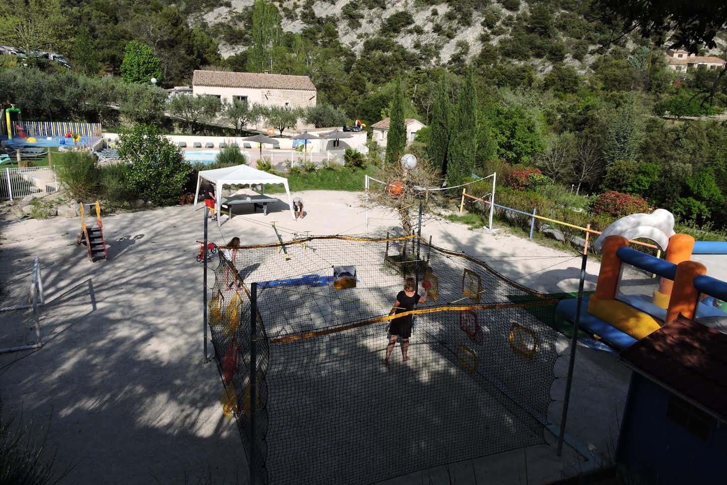 Camping Les Terrasses Provençales - Spielplatz mit Hüpfburg, Volleyballnetz und kleiner Rutsche