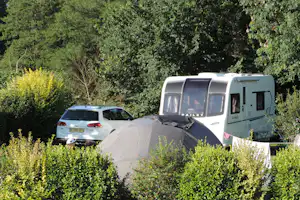 Camping L'escapade - Blick auf Wohnwagenstellplatz zwischen den Bäumen auf dem Campingplatz