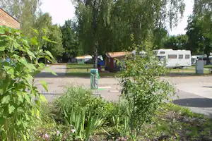 Camping Linz Pichlingersee - Wohnwagenstellplätze und Sanitärgebäude zwischen den Bäumen auf dem Campingplatz